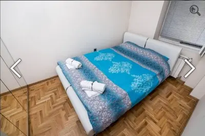 a small bedroom with a bed with a blue blanket at Višegradska in Sajmište