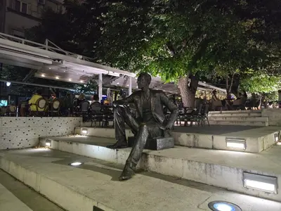 a statue of a man sitting on a bench at Angelina 03. in Belgrade