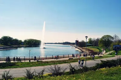 a group of people walking around a lake with a fountain at Cozy green house (free parking spot) in Belgrade