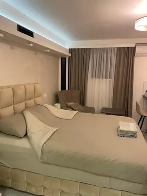 a bedroom with a large bed and a chair at Liga apartment in Vračar (historical)