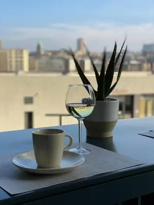 a glass of wine and a cup and a plant on a table at Lolita Lux - Belgrade Waterfront in Belgrade