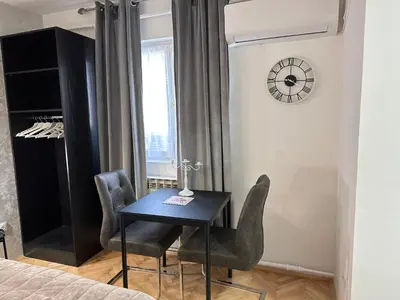 a dining room table with chairs and a clock on the wall at Aster Apartments in Belgrade