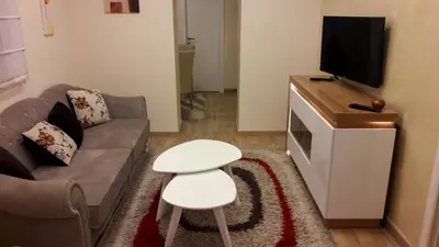 a living room with a couch and a tv and a stool at Apartment Dedinje Hill 2 in Belgrade