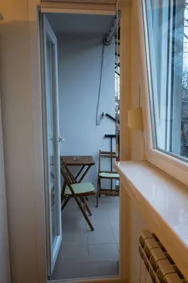 a room with a balcony with a table and a window at Classico apartment Belgrade in Voždovac