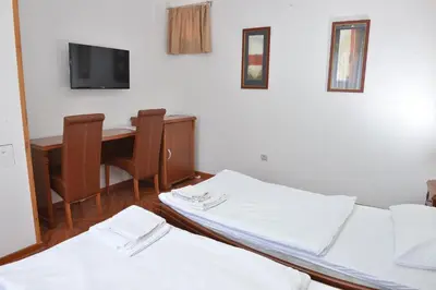 two beds in a room with a desk and a tv at Apartment and Rooms In Club in Inđija