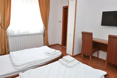 two beds in a room with a desk and a computer at Apartment and Rooms In Club in Inđija