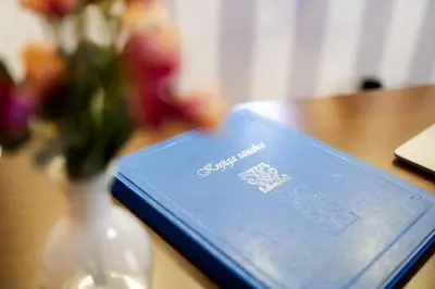 a book on a table next to a vase of flowers at Luka de Luka Suites in Belgrade