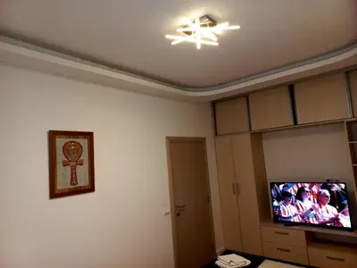 a living room with a tv and a ceiling with a light at Apartment Alex in Belgrade