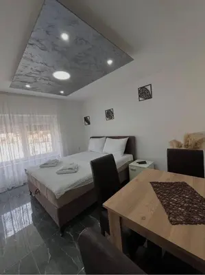 a room with two beds and a table and a dining room at Sobe i Apartmani Casa Mia in Pećinci
