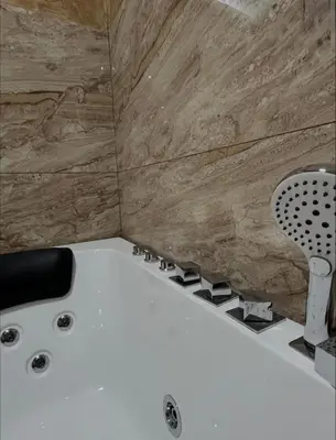a white bath tub in a bathroom with wooden walls at Sobe i Apartmani Casa Mia in Pećinci
