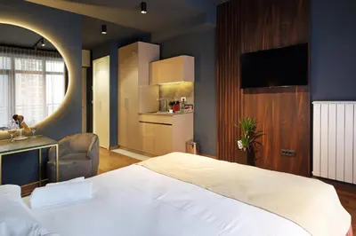 a bedroom with a large white bed and a kitchen at Belgrade Waterfront Apartments - Arcadia in Belgrade