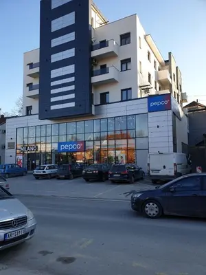 a large building with cars parked in a parking lot at Apartman Magija in Arandjelovac