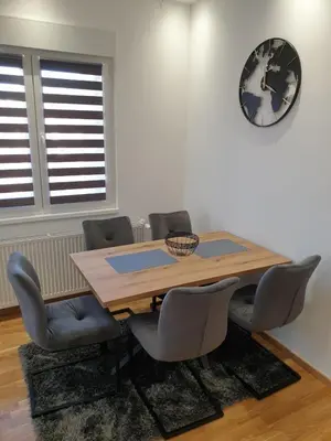 a dining room table with chairs and a clock on the wall at Apartman Magija in Arandjelovac