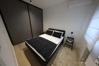 a bedroom with a bed with black and white sheets and pillows at Modern apartment in the heart of Belgrade in Belgrade
