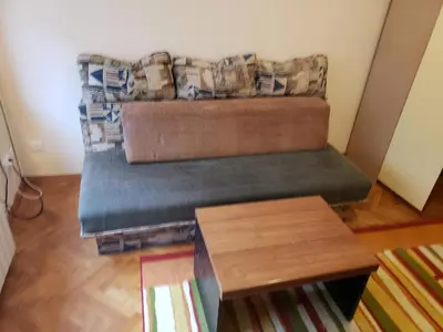 a couch in a living room with a table at Private cozy room 1 with shared kitchen in appartment, downtown Belgrade in Belgrade