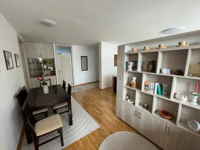 a dining room and living room with a table and shelves at New Belgrade apartment in Belgrade