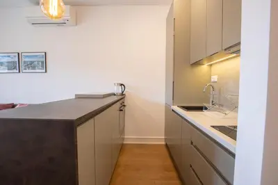 a kitchen with white cabinets and a black counter top at Belgrade Center Apartment Lux Residence in Belgrade