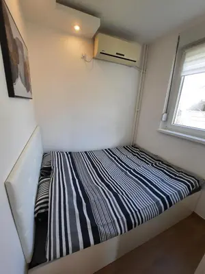 a small bed in a small room with a window at Apartment Piccolo Ada in Belgrade