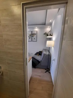 a hallway leading to a bedroom with a couch and a lamp at Apartment Piccolo Ada in Belgrade