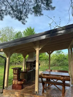 a wooden pavilion with a picnic table and a stove at Vikend-kuca Vevericji Kraj in Vranić