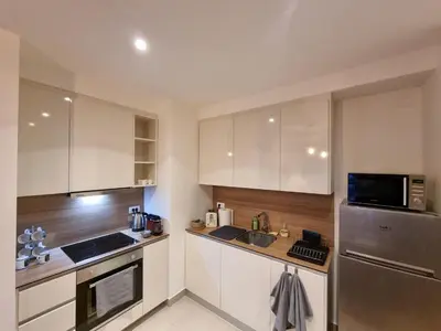 a kitchen with white cabinets and a stainless steel refrigerator at BW Arcadia deluxe apartments in Sajmište