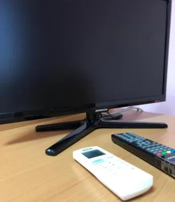 a computer monitor and a remote control on a desk at Sara Apartment in Surčin