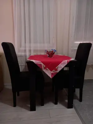 a table with a red table cloth on it with two chairs at Sara Apartment in Surčin