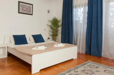 a white bed in a room with blue curtains at Red Clay Apartments City Club in Belgrade