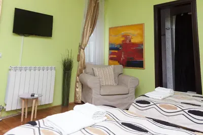 a living room with a chair and a television at Red Clay Apartments City Club in Belgrade
