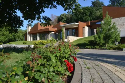 a house with red flowers in front of a street at Villa Luxury Rooms - Wine Resort in Smederevo