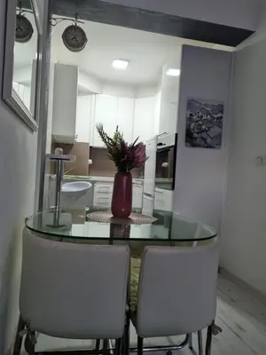 a kitchen with a glass table and two white chairs at Downtown lux in Smederevo