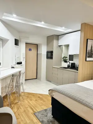 a bedroom with a bed and a kitchen with white cabinets at Paradise Museum City Center in Belgrade