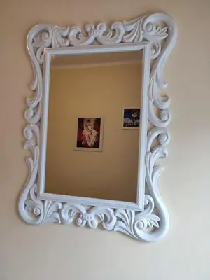 a mirror with a white frame on a wall at Orion Apatman in Belgrade