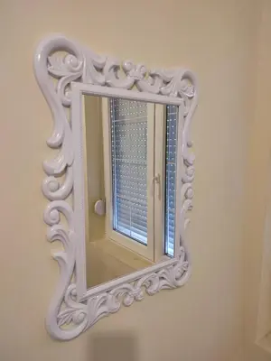 a mirror with a white frame on a wall at Orion Apatman in Belgrade