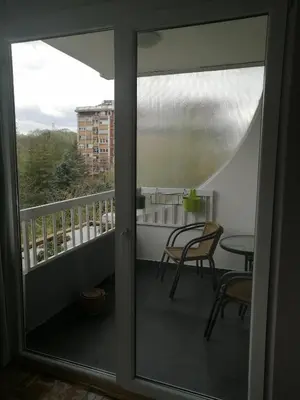 a balcony with a glass door with a table and chairs at Green 1 in Belgrade