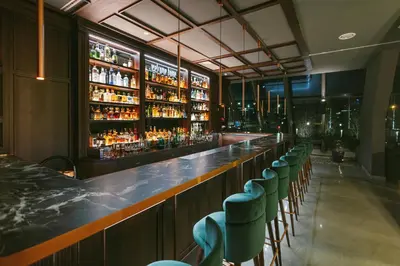 a bar with a row of green chairs and alcohol bottles at Crowne Plaza Belgrade by IHG in Belgrade