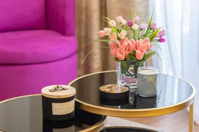 a table with a vase of flowers and a pink chair at Belgrade Waterfront Studio Apartment-Supertwins in Sajmište