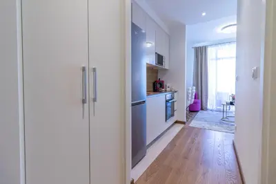 a kitchen with white cabinets and a wooden floor at Belgrade Waterfront Studio Apartment-Supertwins in Sajmište