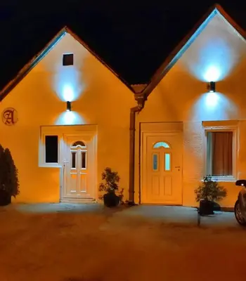 a house with lights on the front of it at night at Stan na dan studio in Inđija