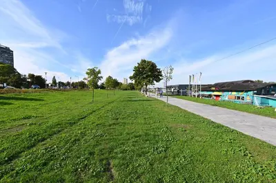 a grassy field next to a sidewalk and buildings at Hidden Gem in Belgrade