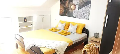 a small bedroom with a bed with yellow pillows at Apartman Blagojevic Hill in Arandjelovac