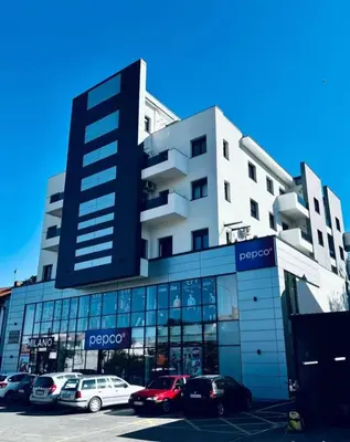 a large building with cars parked in a parking lot at Apartman Blagojevic Hill in Arandjelovac