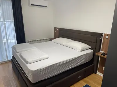 a bed with a black frame and white sheets and pillows at Princess - free parking place in the garage in Belgrade