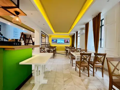 a restaurant with tables and chairs and yellow ceilings at Side One Design Hotel Garni in Belgrade