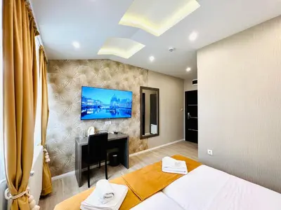 a bedroom with a desk and a tv on a wall at Side One Design Hotel Garni in Belgrade