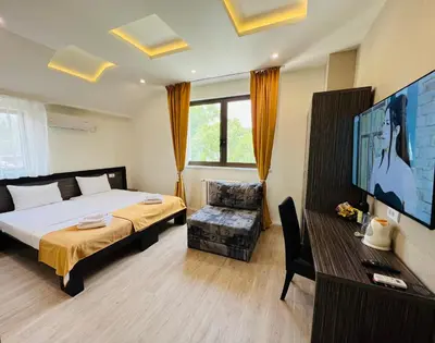 a bedroom with a bed and a tv and a chair at Side One Design Hotel Garni in Belgrade