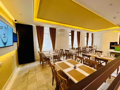a restaurant with tables and chairs and a flat screen tv at Side One Design Hotel Garni in Belgrade