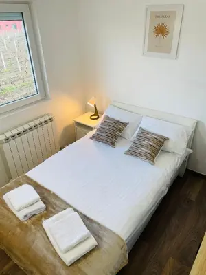 a bedroom with a white bed with two pillows and a window at Muki apartments in Surčin