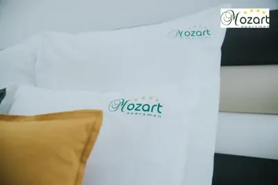 a white wall with a couch and two logos on it at Mozart-Apartman in Arandjelovac