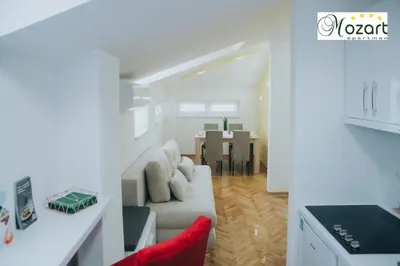 a white living room with a couch and a table at Mozart-Apartman in Arandjelovac